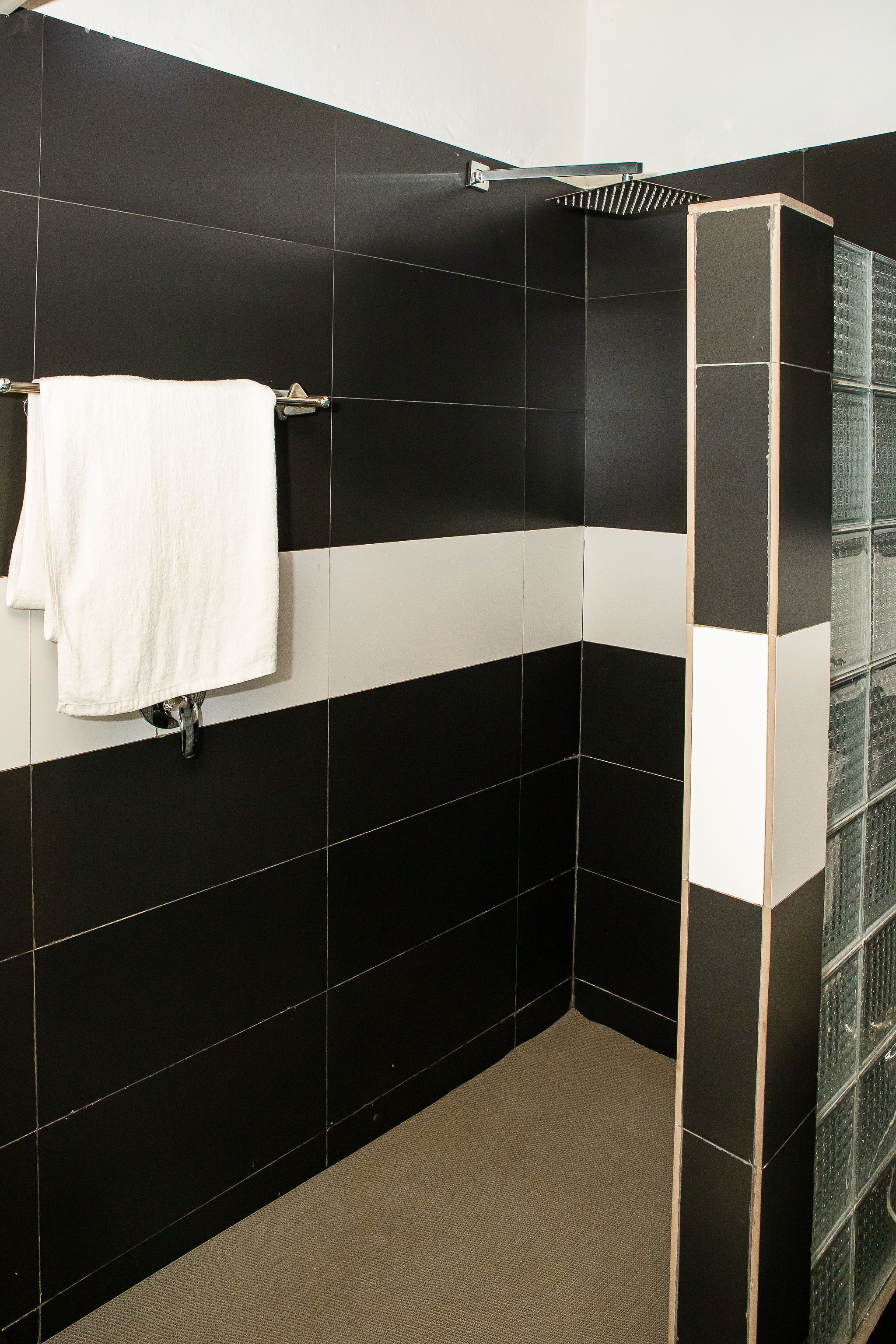 A bathroom with black and white tiles, a white towel hanging on a rack, and a glass shower enclosure.
