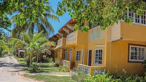 A row of yellow buildings with balconies, surrounded by palm trees and greenery. - Columbus Inn (St. Ann's Bay)