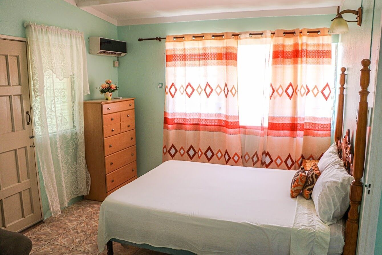 Un dormitorio con cama, cómoda y cortina.