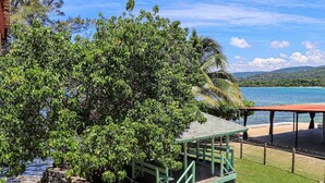 A beachside structure with a covered seating area and a staircase leading down to the beach. - Columbus Inn (St. Ann's Bay)