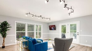 A living room with a blue sofa, a grey armchair, a glass coffee table, and a potted plant. - Charlotte Pondside Oasis (Charlotte)