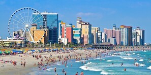 A beach with a Ferris wheel and a city skyline in the background.