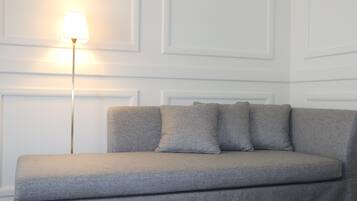 A neutral-toned sofa with a single lamp against a white paneled wall.