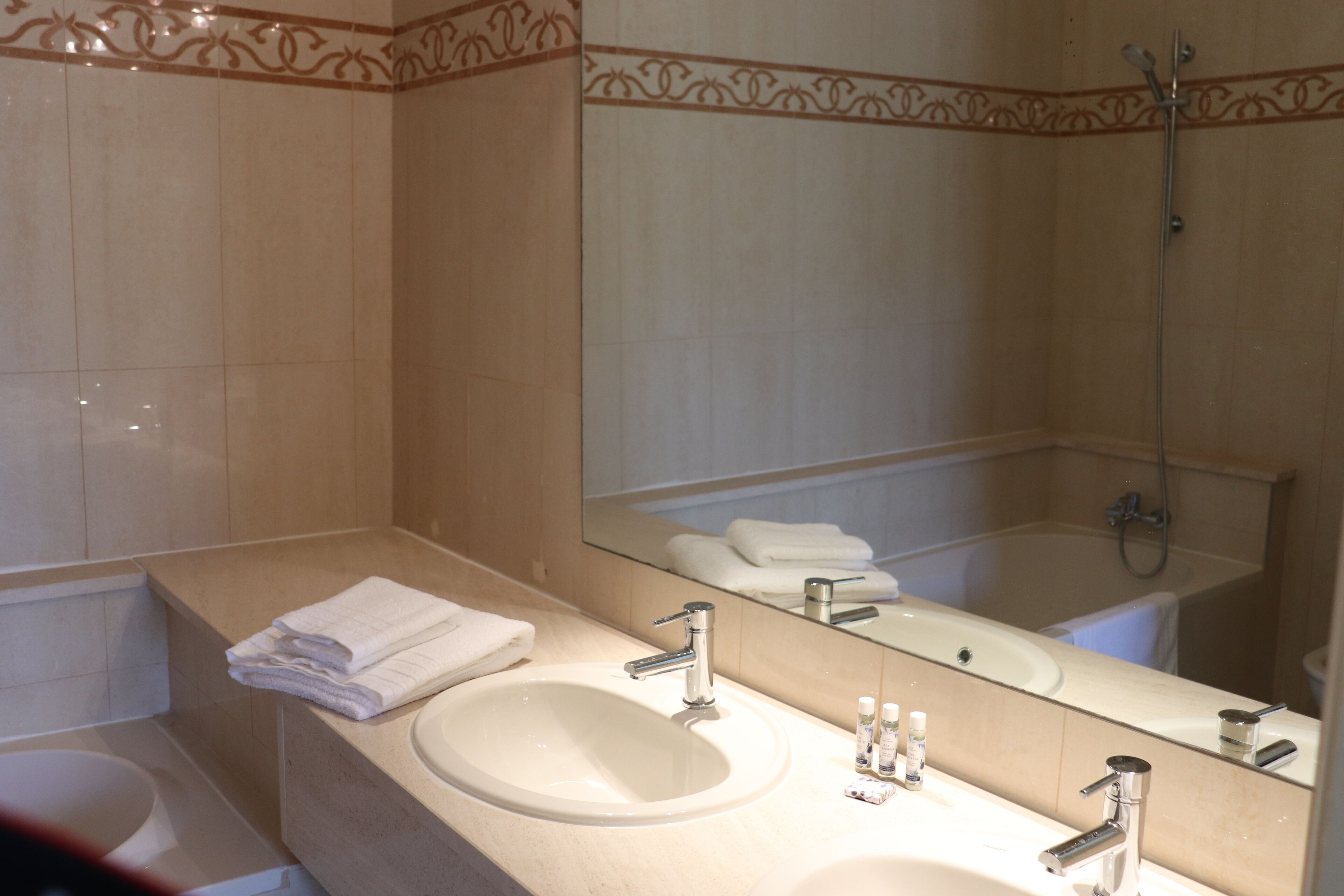 A bathroom with a sink, mirror, and shower.