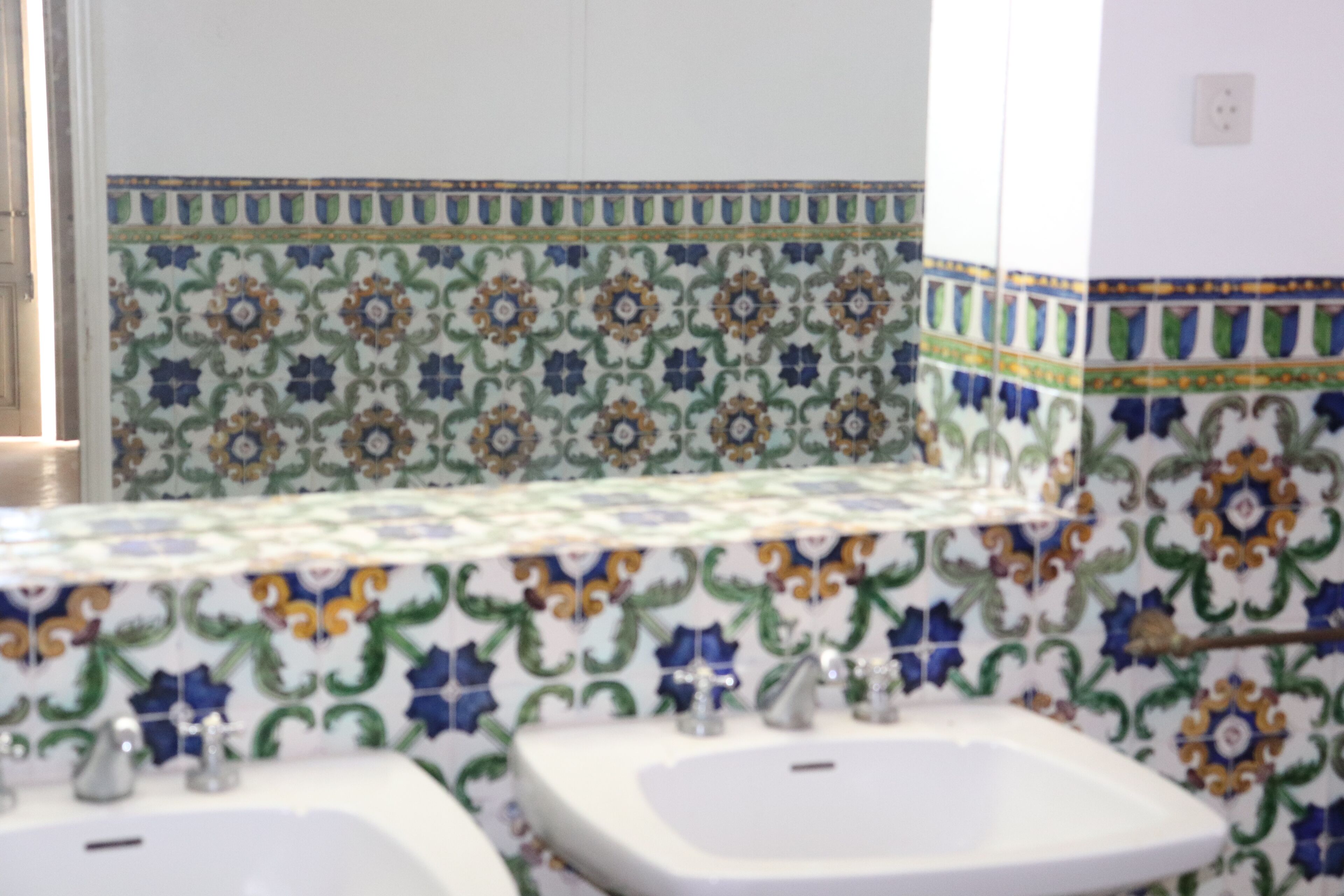 Une salle de bain avec deux lavabos et des motifs décoratifs en carreaux sur les murs.