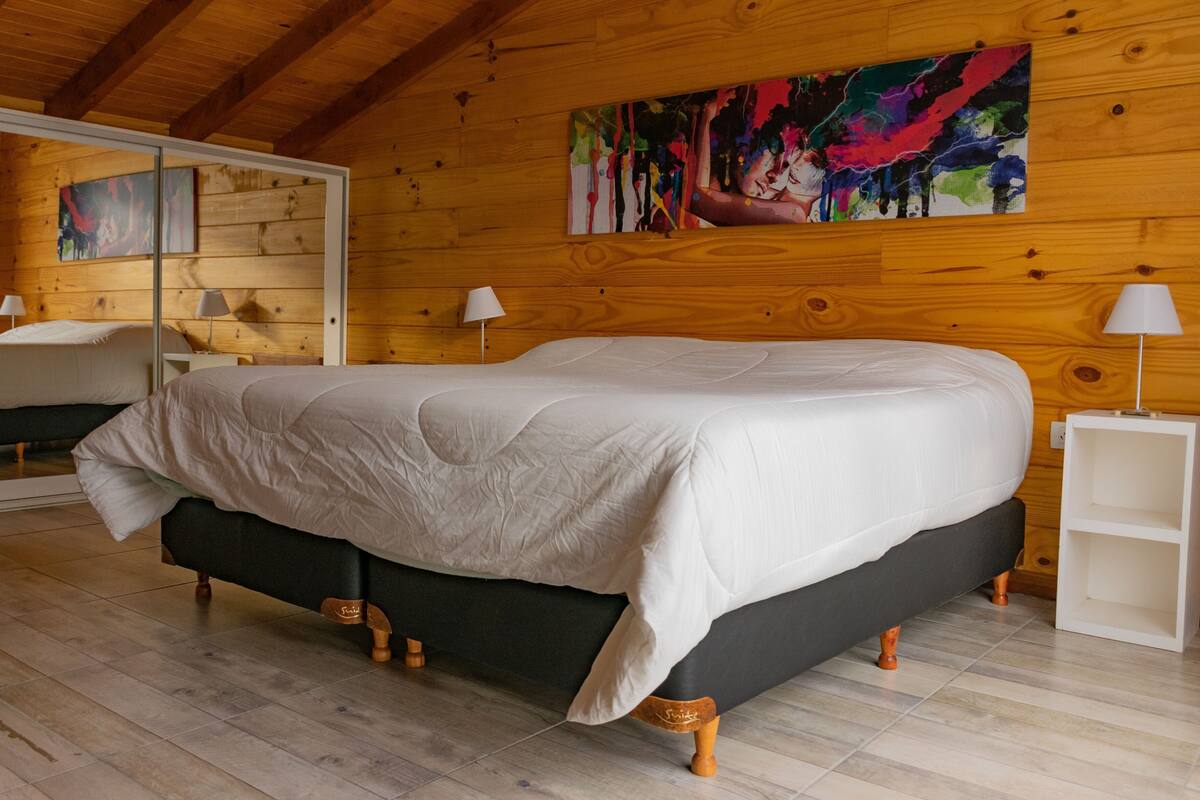 Une chambre à coucher avec un lit, des murs en bois, un tableau et une table de chevet.