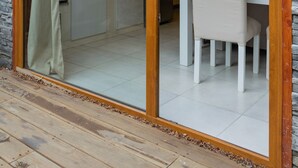 A wooden-framed sliding glass door leading to a dining area with a table and chairs. - Los AMANCAYS (Villa La Angostura)