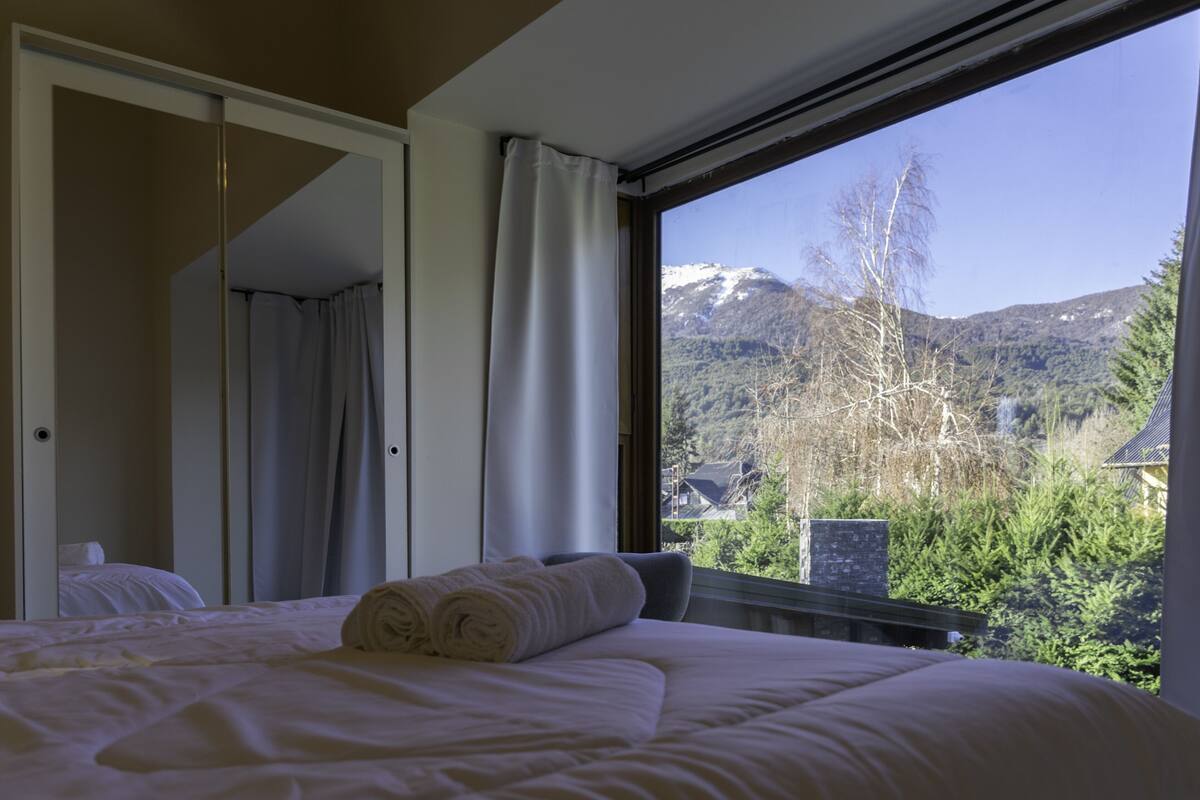 Une chambre à coucher avec un lit, une fenêtre et une vue sur une montagne.