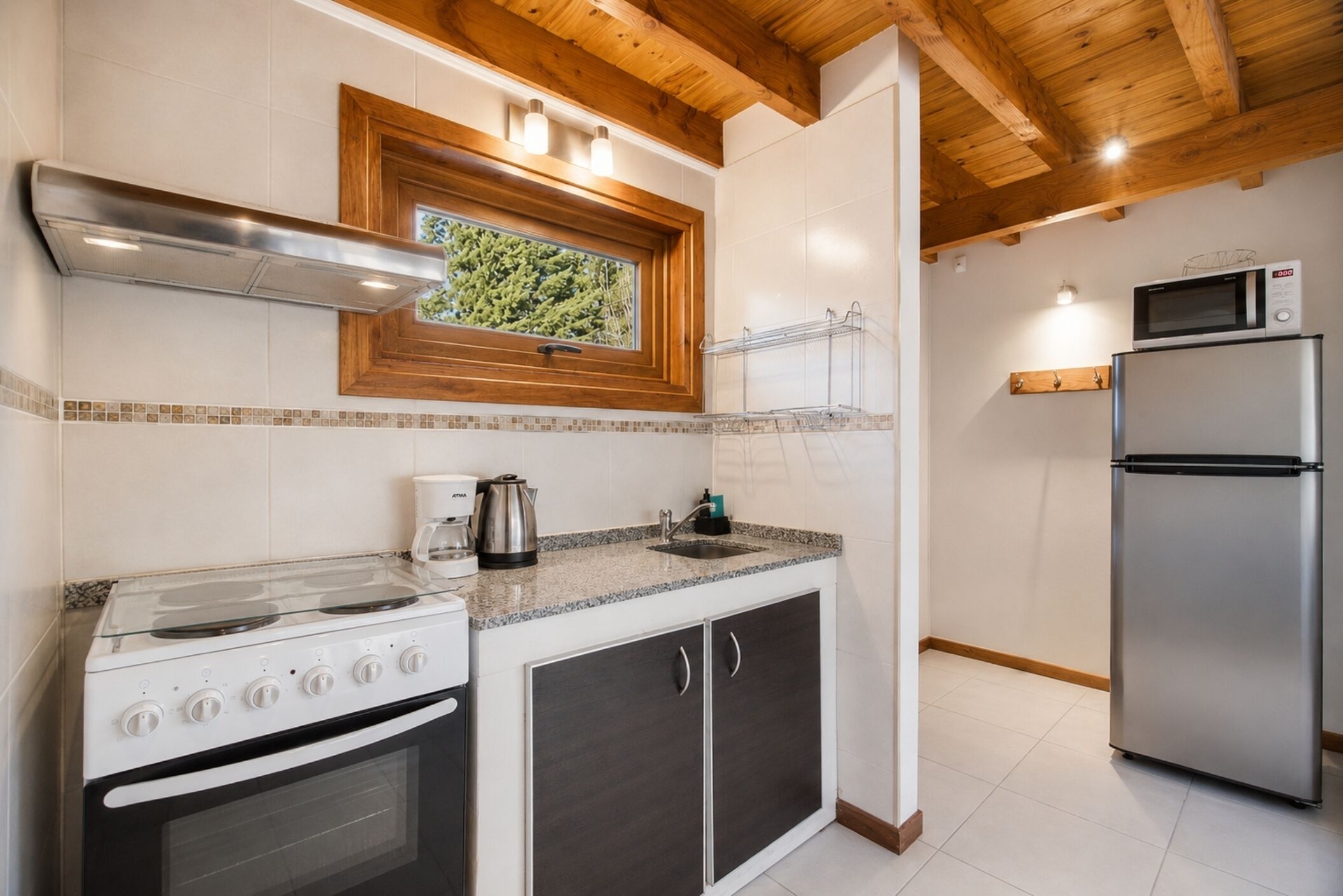 A compact kitchen with a gas stove, oven, microwave, and a small window.