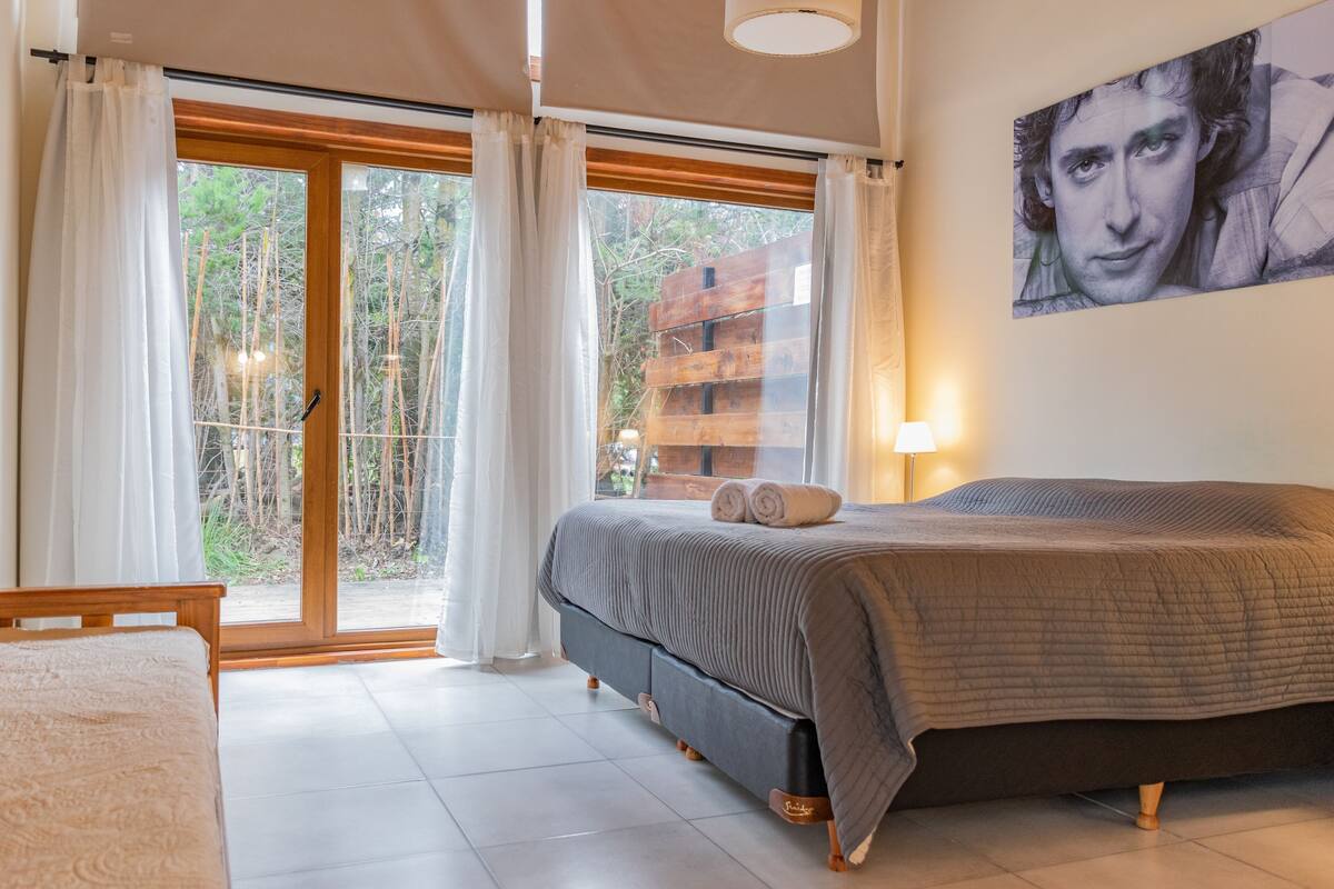 Une chambre à coucher avec un lit, des rideaux, une fenêtre et une lampe fixée au mur.