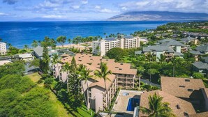A coastal residential area with a large hotel featuring multiple stories, a swimming pool, and a view of the ocean. - Ocean view 1 bedroom, AC, walk to shops, dining, & beaches (Kihei)