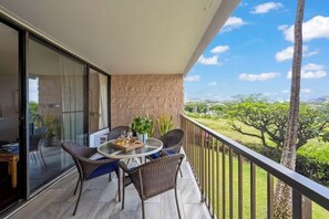 Un balcon avec une table, des chaises et une vue sur la verdure et les bâtiments éloignés.