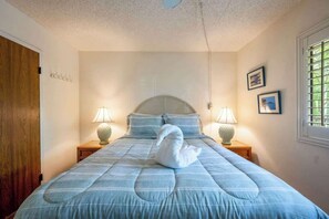 Une chambre à coucher avec un lit, deux lampes de chevet, un coussin en forme de cygne et une fenêtre avec des stores.