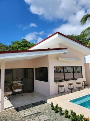 Una casa moderna con piscina, ventanas amplias y un patio cubierto.