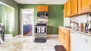 A compact kitchen with green walls, wooden cabinets, and a stainless steel oven. - Historical Blvd. Cheney Bros HillTop Mansion (Manchester)