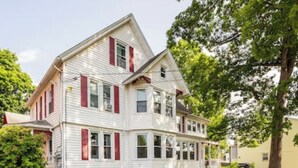 A two-story house with a gabled roof, a front porch, and a large tree in the background. - Historical Blvd. Cheney Bros HillTop Mansion (Manchester)