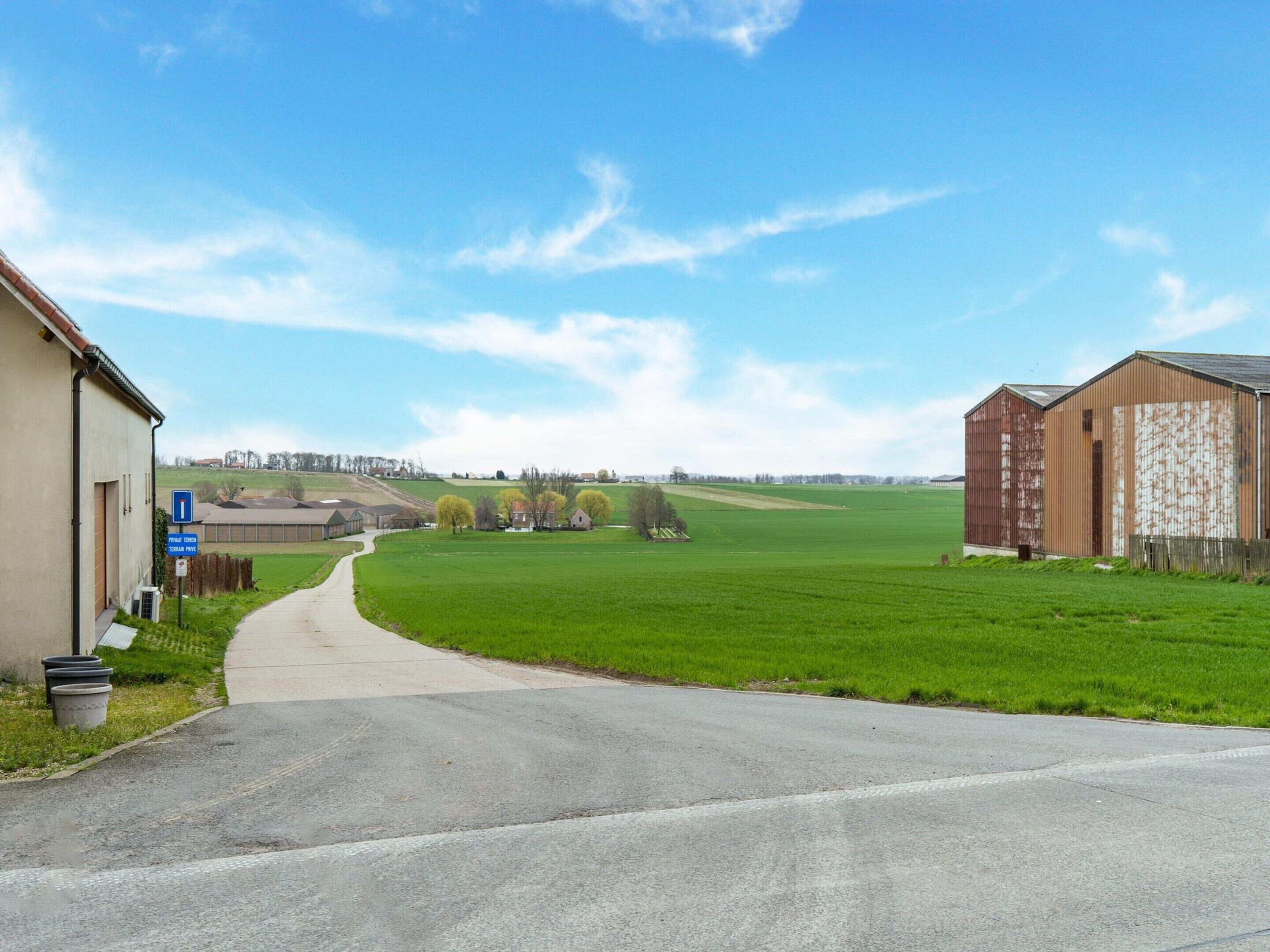 Eine Landstraße, die zu einem Gebäude mit einem blauen Schild für eine Privatstraße führt.
