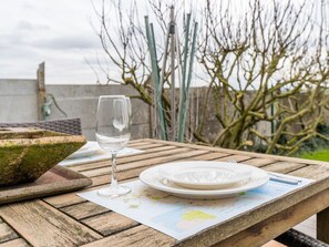 A wooden table with a map, a wine glass, and a plate with cutlery. - Pet-friendly Retreat (Heuvelland)