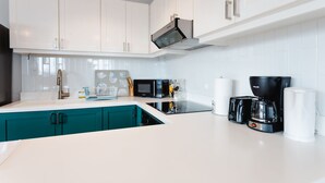 A modern kitchen with white cabinets, a black coffee maker, and a microwave. - Casa Love 3B (Panama City)