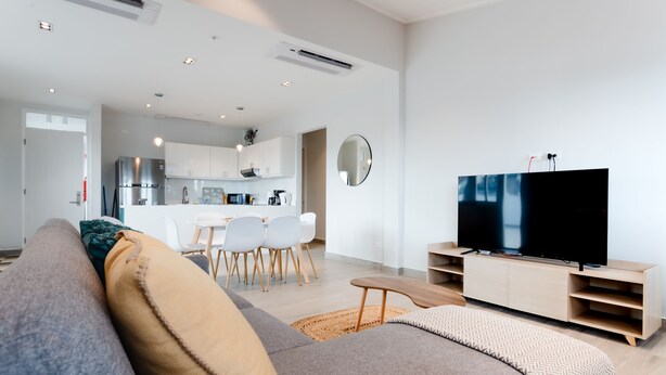 A modern living room with a large flat-screen TV, a sofa, and a dining area with chairs and a table. - Casa Love 3B (Panama City)