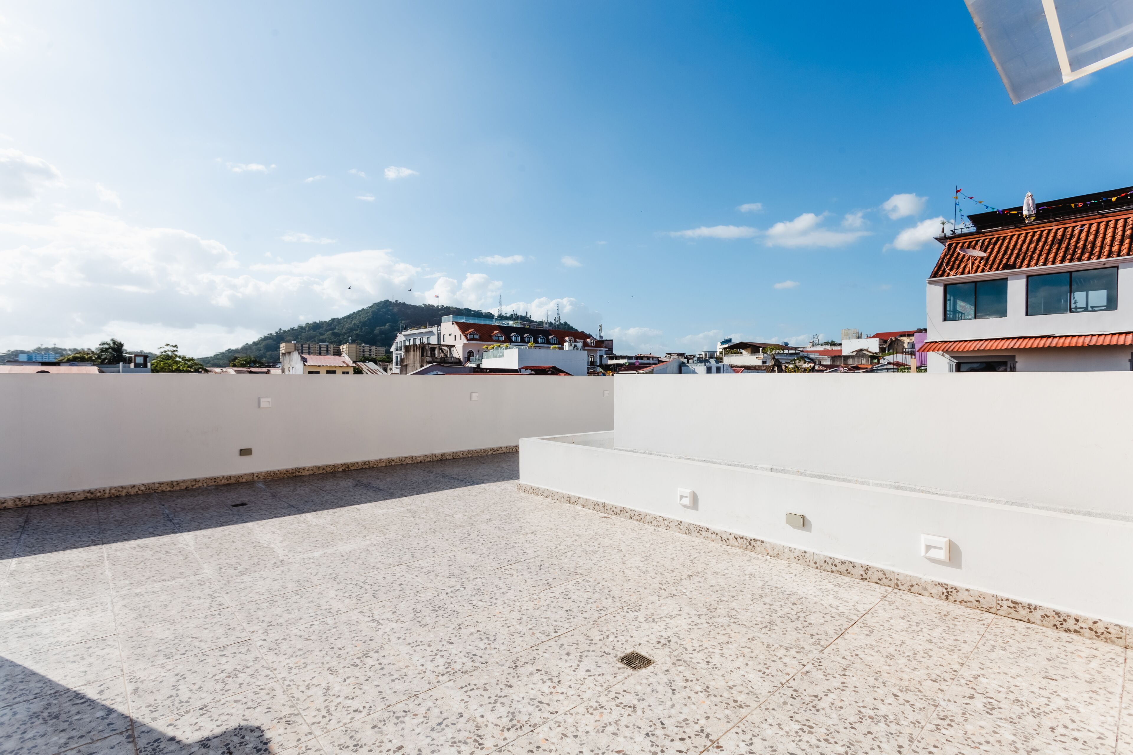 Eine Dachterrasse mit freiem Blick auf die Stadtlandschaft, einschließlich Gebäude und einer entfernten Hügelkette.