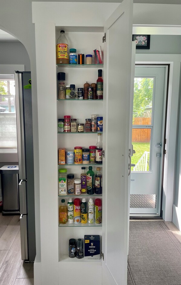 A kitchen pantry with various food items and condiments.