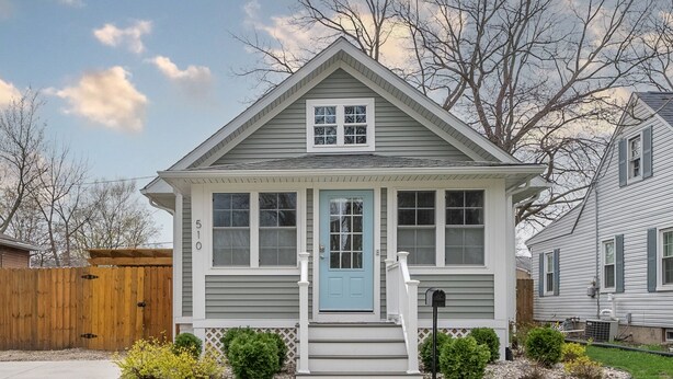 Une maison de plain-pied avec une porte d’entrée bleue, des boiseries blanches et un petit porche.