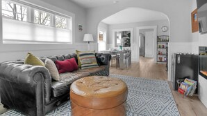 Un salon spacieux avec un canapé en cuir, un pouf et un tapis à motifs.