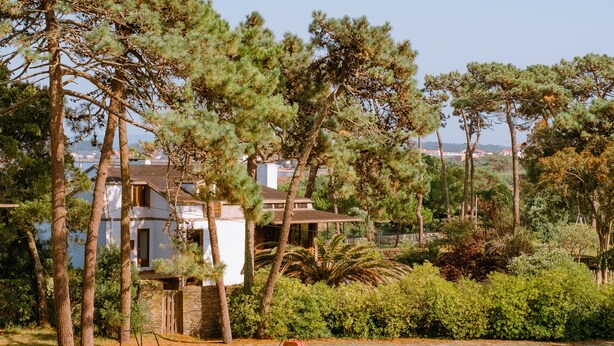 A swimming pool with a clear view of a building in the background, surrounded by trees and greenery. - Parque do Rio Ofir Hotel (Esposende)
