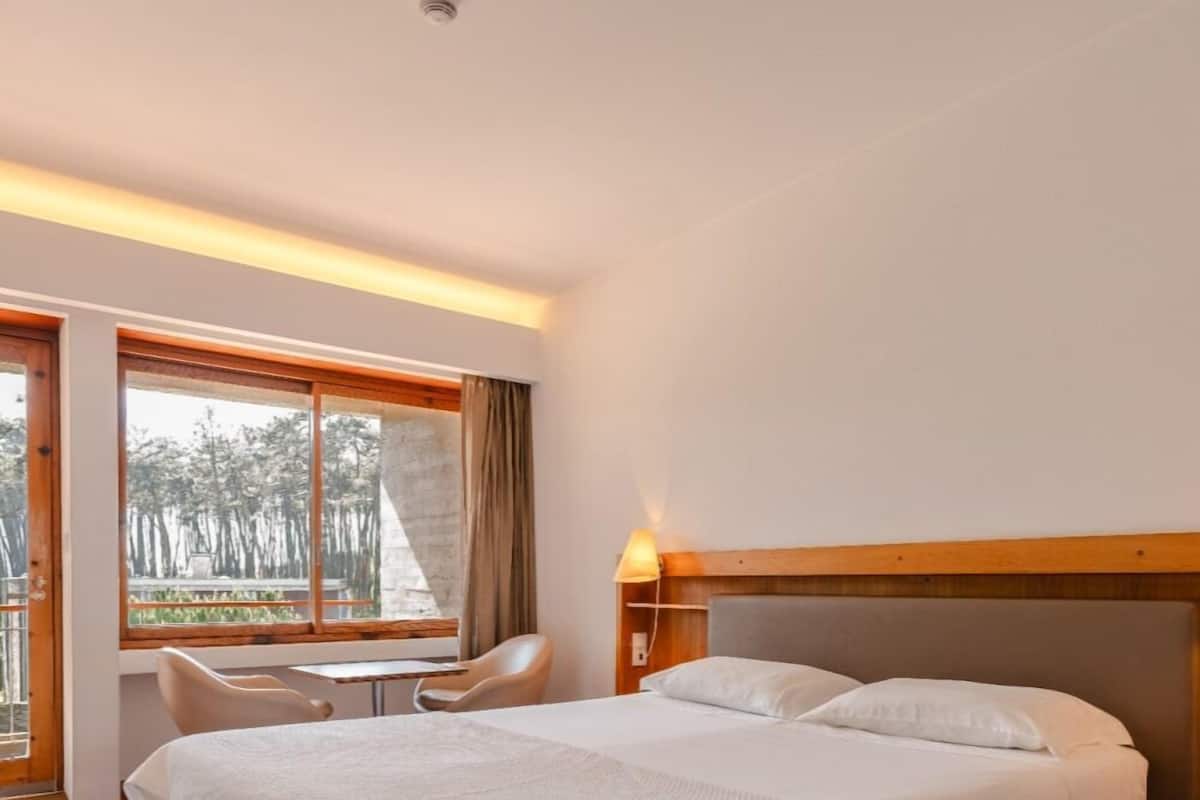 A hotel room with a bed, a desk, and a chair.