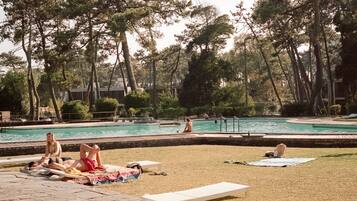 A pool area with lounge chairs and a grassy area.