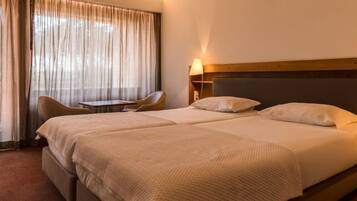 A hotel room with a large bed, a chair, a small table, and a lamp.