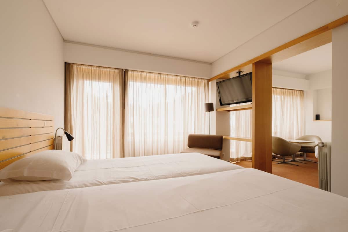 A hotel room with two beds, a TV, a desk, and a chair.