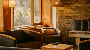 A cozy room with wooden walls, a stone fireplace, and a comfortable seating area with a sofa and chairs. - Parque do Rio Ofir Hotel (Esposende)