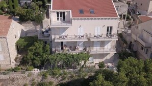 A two-story building with a red-tiled roof, a balcony on the upper floor, and a satellite dish on the lower floor. - Begovic Guest House - One-bedroom Apartment (Dubrovnik)