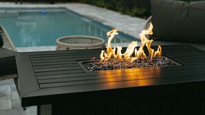 A poolside area with a fire feature and string lights. - Coastal Getaway With Bikes & NEW Saltwater Pool (Sarasota)