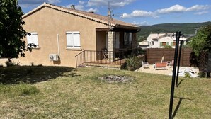 A two-story house with a balcony, a small outdoor seating area, and a stone fireplace. - Belle Maison Rénovée Avec Jardin, à 500m du Centre Village (Goudargues)