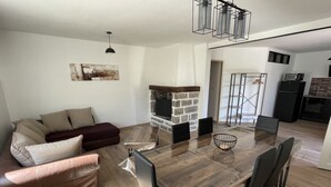 A modern living room with a wooden dining table, leather sofa, and a fireplace. - Belle Maison Rénovée Avec Jardin, à 500m du Centre Village (Goudargues)