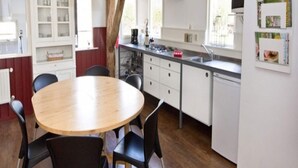 A modern kitchen with white cabinets, a round wooden table, and black chairs. - Holiday Home in Former Barn in Ruinerwold (Ruinerwold)