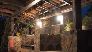 An outdoor patio area with stone walls and wooden beams. - Tierra Mia Hacienda Ruta del Vino (Valle de Guadalupe)