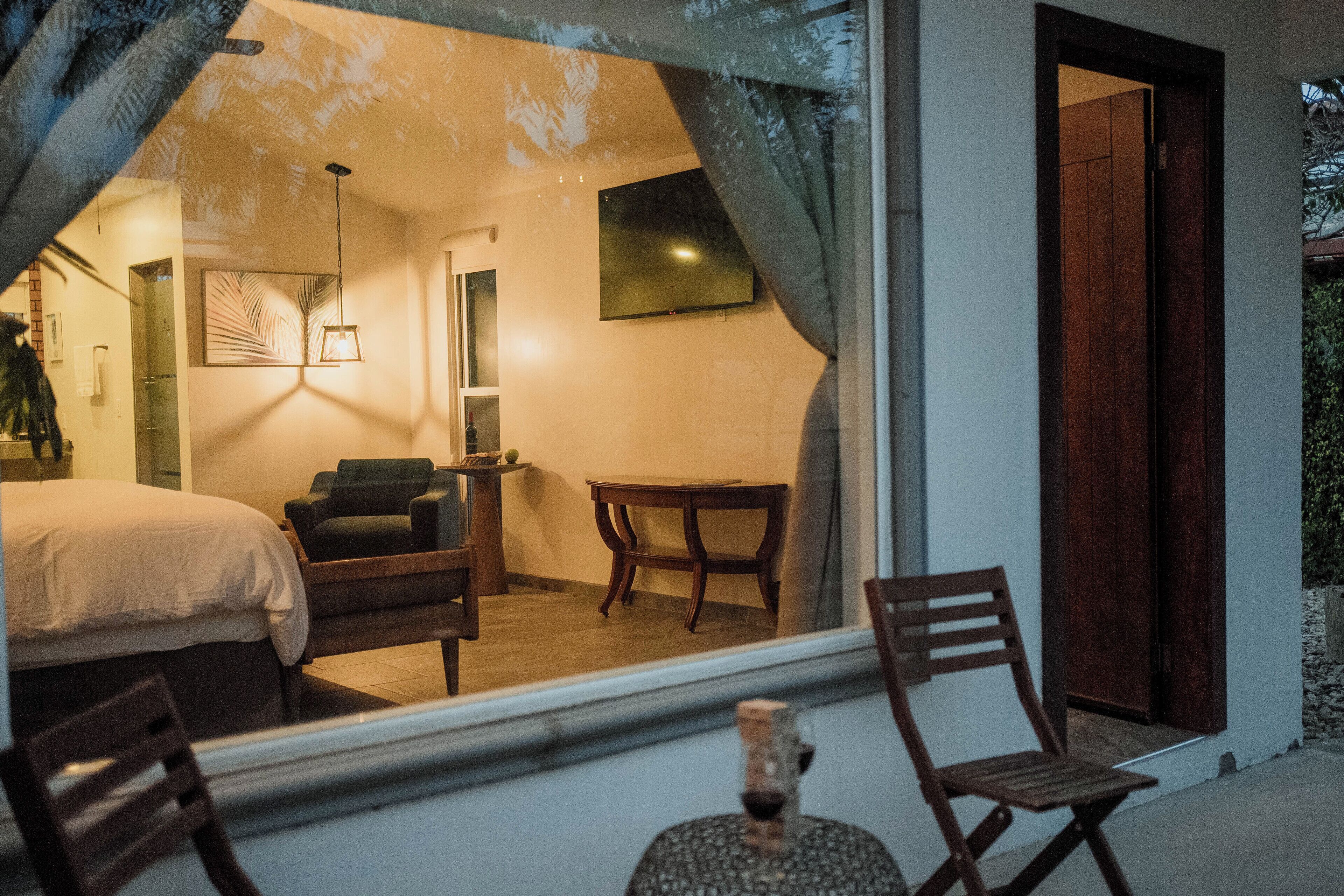 Une pièce avec un lit, une chaise, une table et un téléviseur fixé au mur.