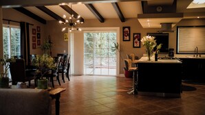 A spacious living area with a large window, a dining table, chairs, a coffee station, and a kitchen area. - Tierra Mia Hacienda Ruta del Vino (Valle de Guadalupe)