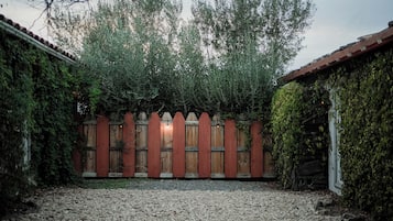 A courtyard with a gravel path, wooden fence, and a wooden building with a tiled roof.