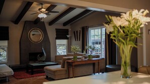 A living room with a fireplace, a ceiling fan, and a large window. - Tierra Mia Hacienda Ruta del Vino (Valle de Guadalupe)