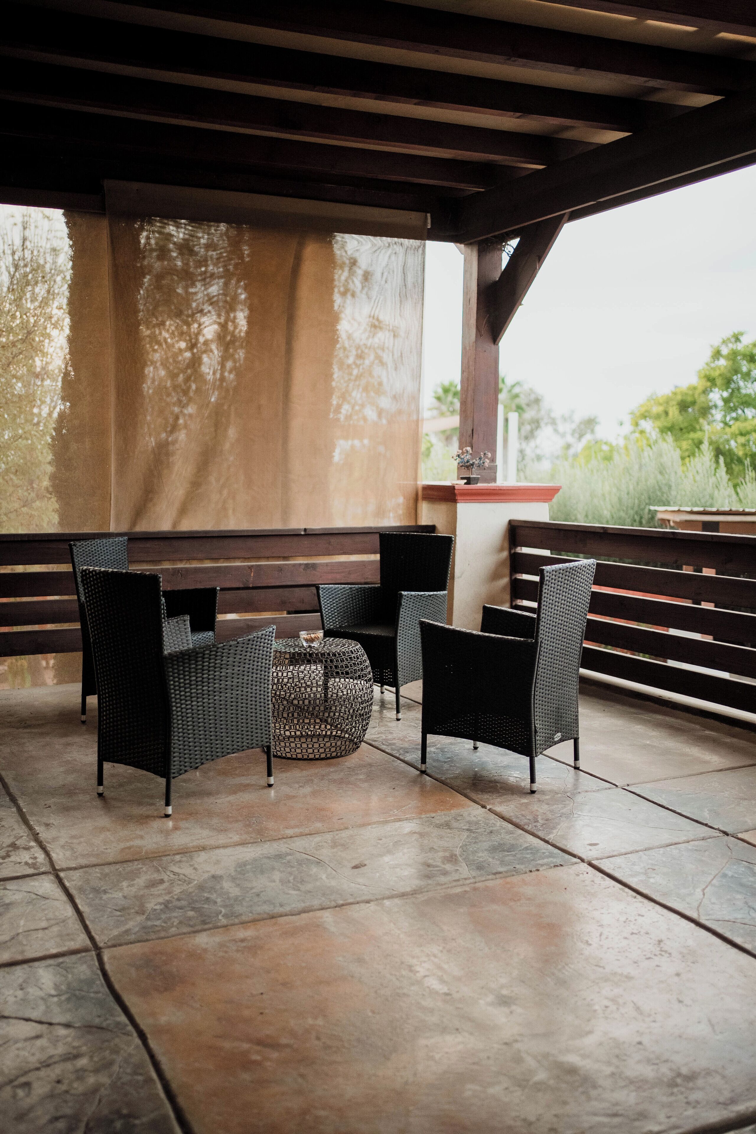 An outdoor patio area with wicker furniture and a stone floor.