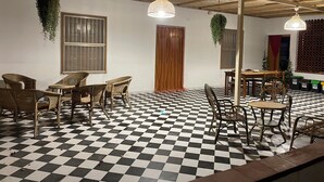 Une pièce avec un sol à carreaux, des meubles en osier et des plantes suspendues.