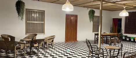 A room with a checkered floor, wicker furniture, and hanging plants.