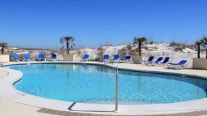 A swimming pool with blue chairs and a view of the beach. - Beautifully Decorated Beachfront Condo! (Orange Beach)