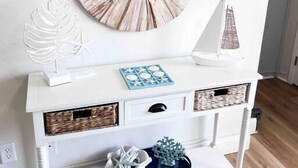 A white console table with a round mirror, decorative items, and storage baskets. - Beautifully Decorated Beachfront Condo! (Orange Beach)