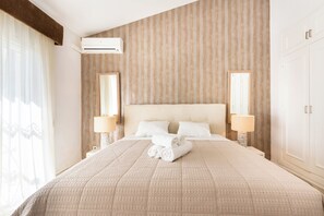 A hotel room with a large bed, two bedside lamps, a mirror, and a window with curtains.